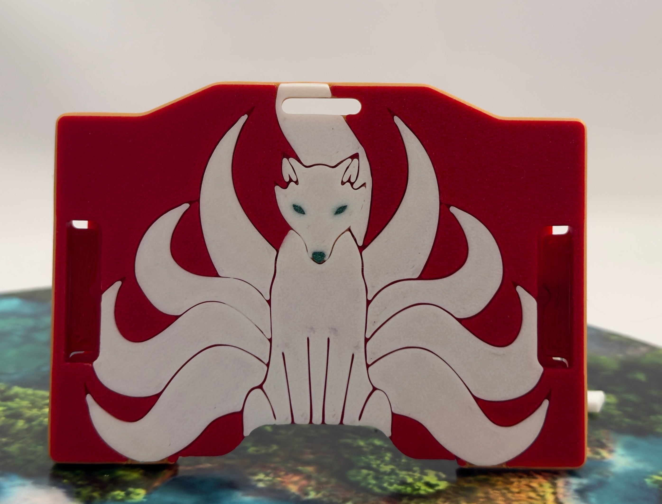 A red keycard holder featuring a white Kitsune fox design on the front