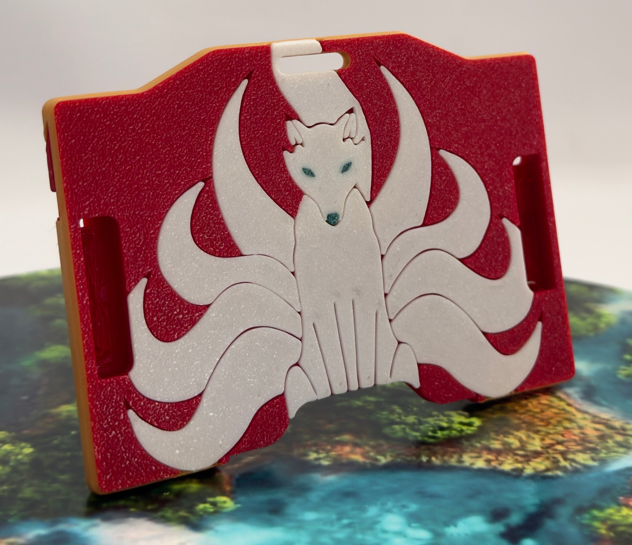 A red keycard holder featuring a white Kitsune fox design on the front
